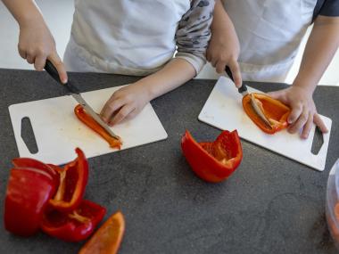 Børn skærer røde peberfrugter ud